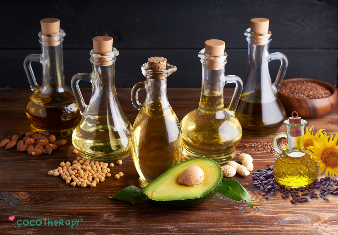 Different bottles of seed oils, such as avocado oil, peanut oil, soybean oil, sunflower oil, on a table.